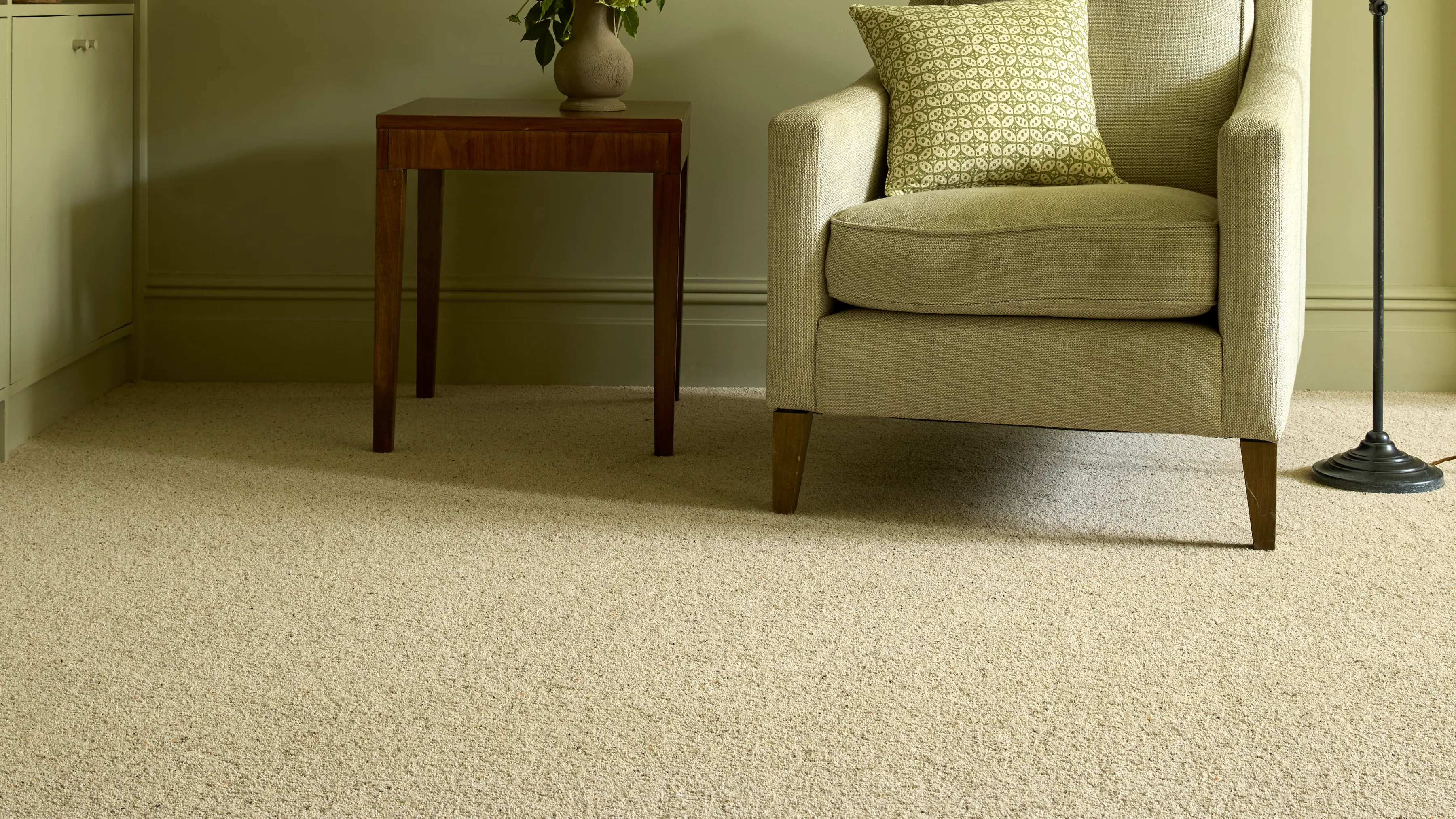 An olive green sitting room with a natural berber twist carpet