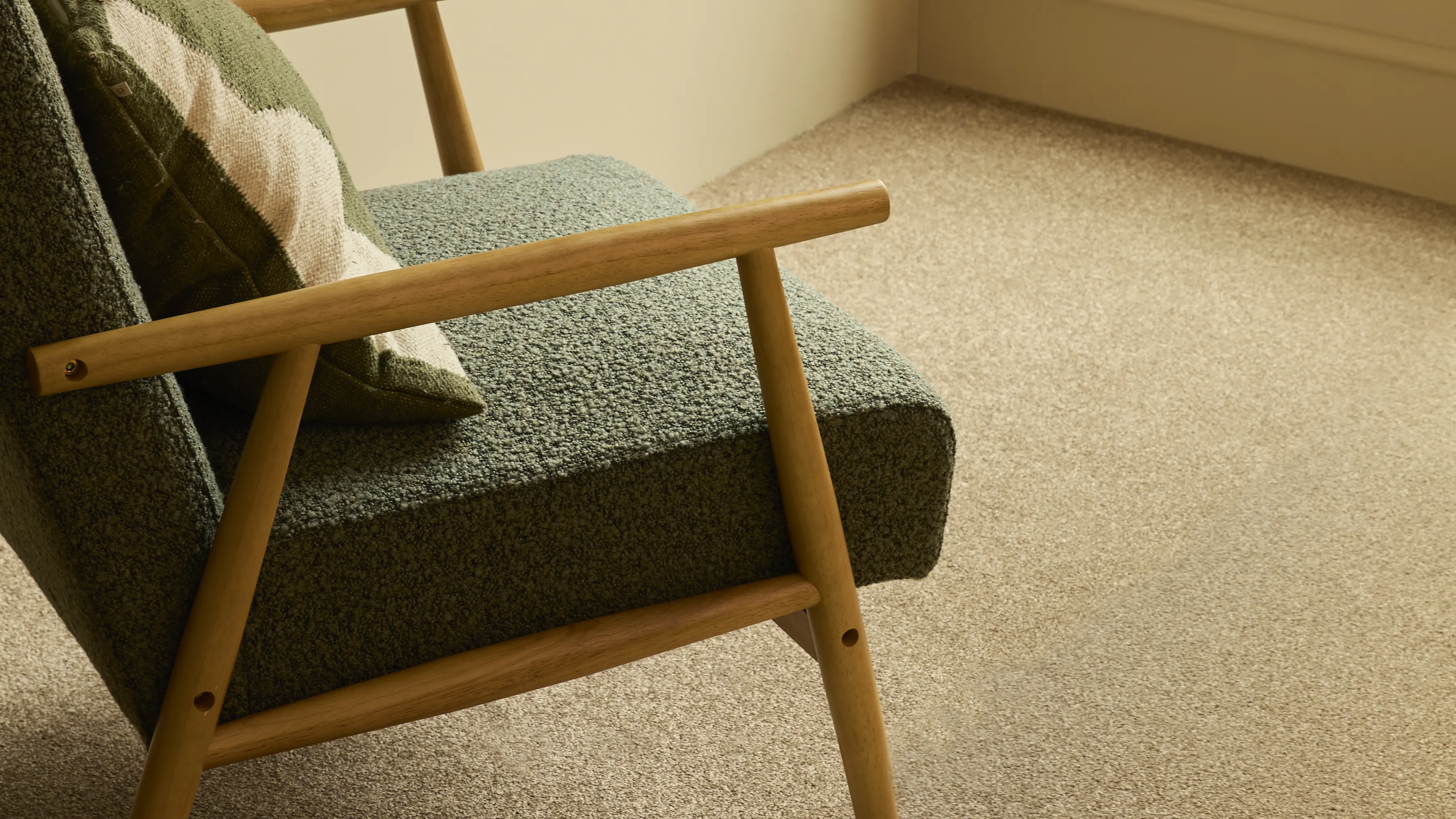 A green armchair on a cream wool carpet in a bay window