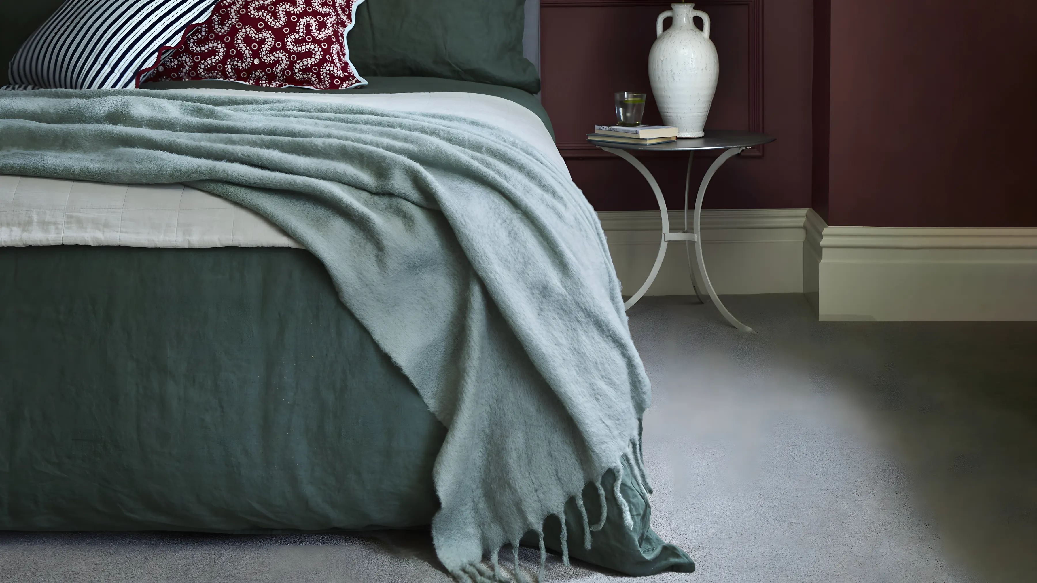 A bedroom with deep red walls and a soft grey carpet