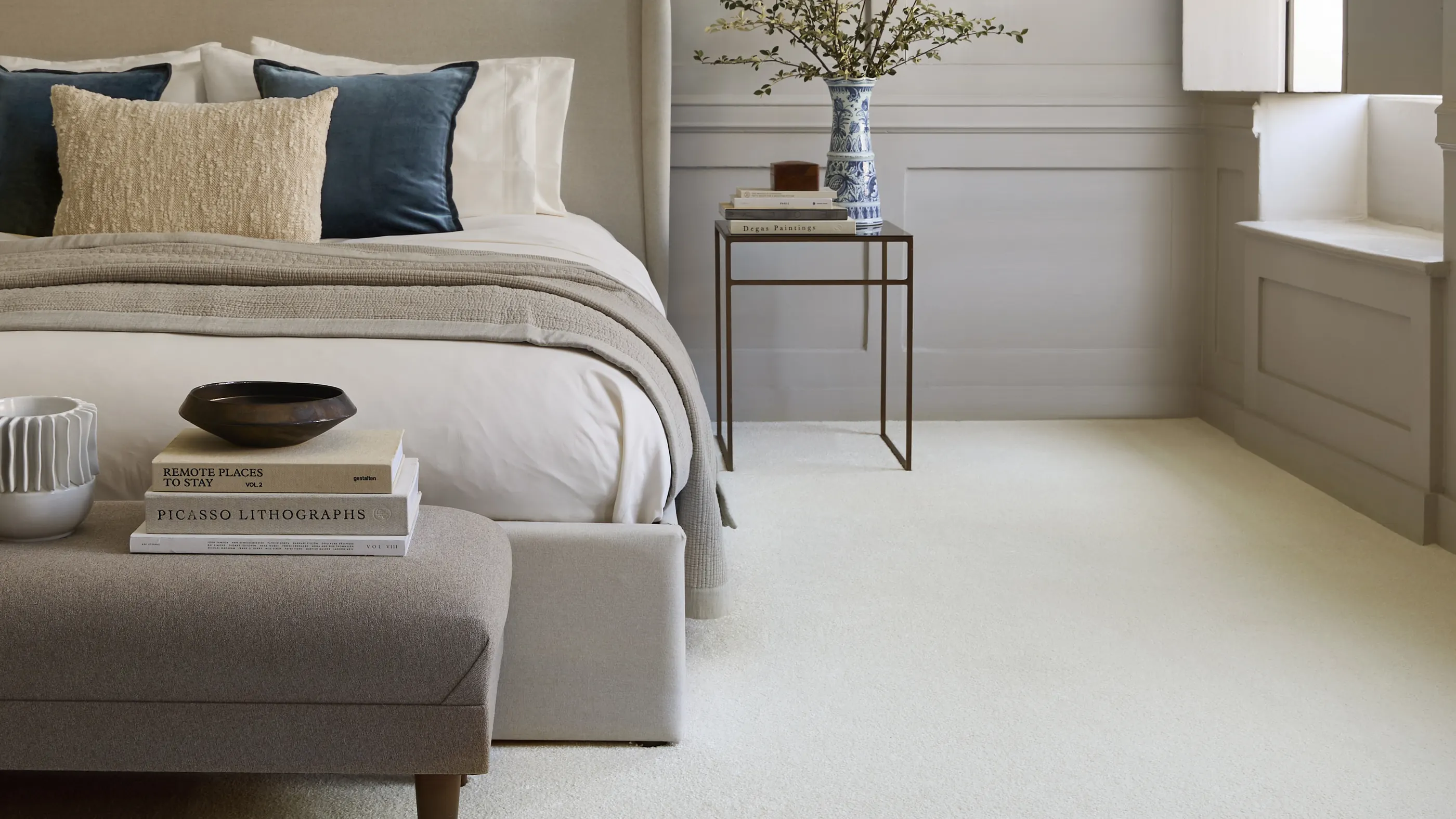 A bedroom with a deep cream carpet and a pale headboard
