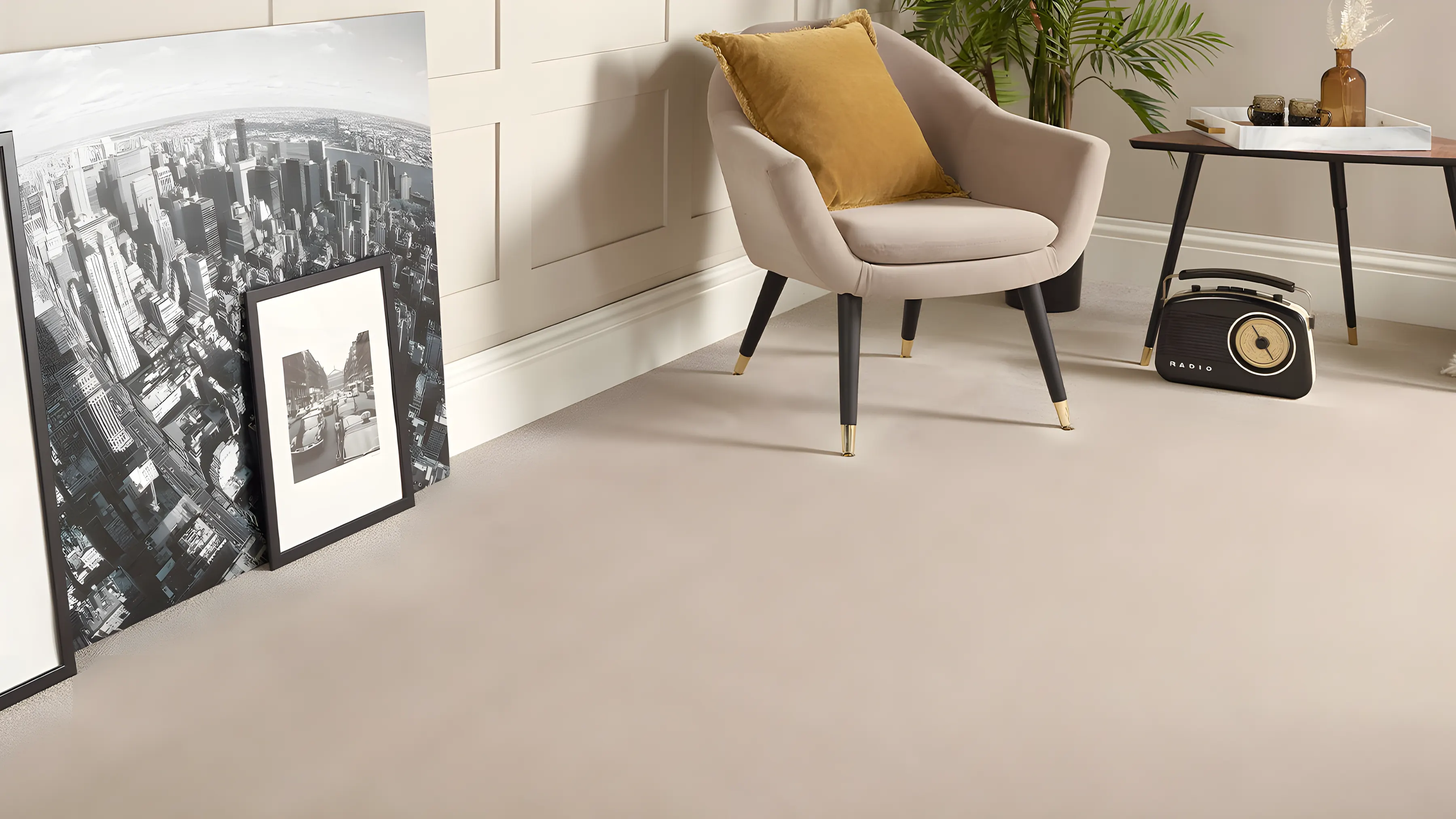 A light carpet in a sitting room with framed prints and an armchair