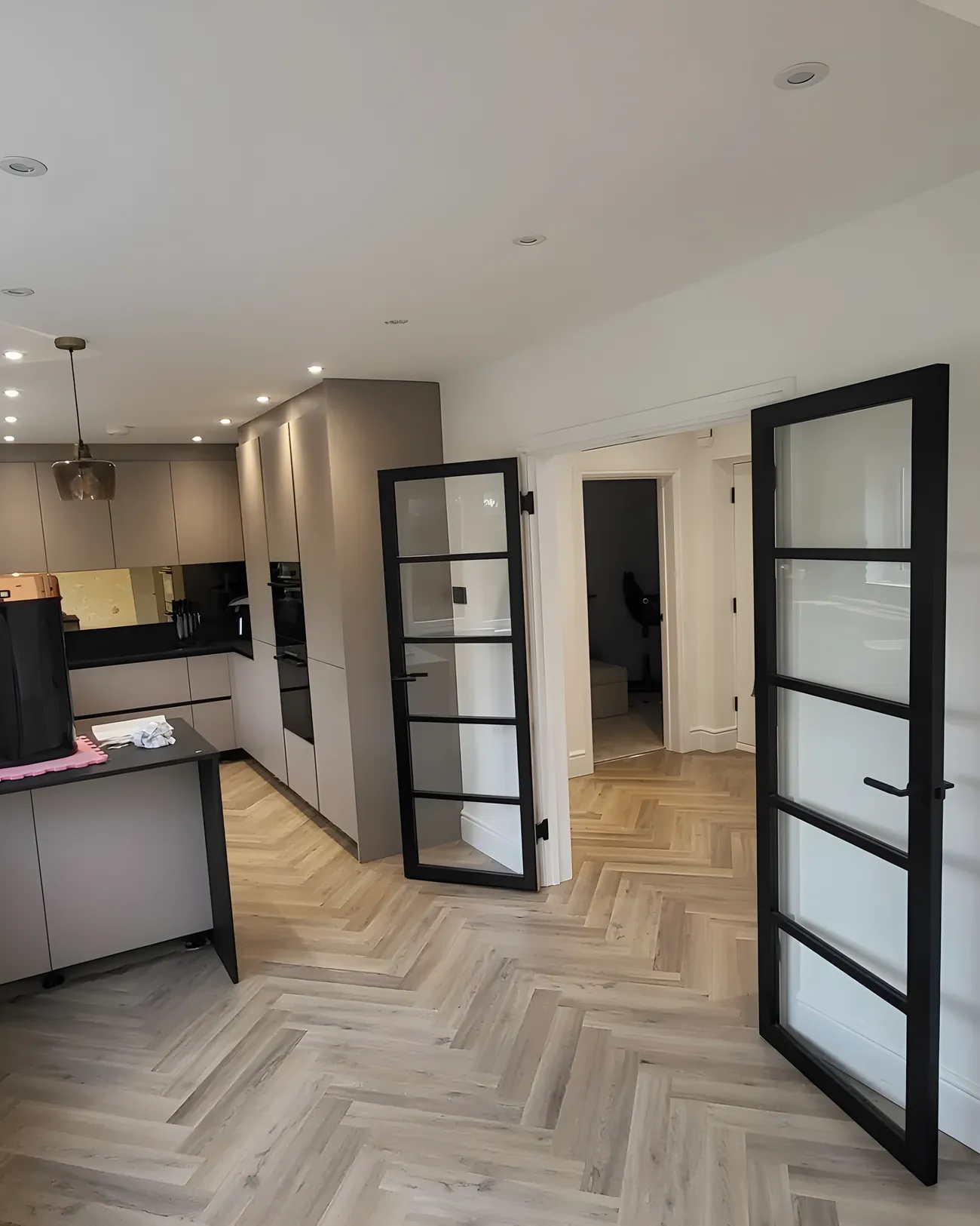 A kitchen with a wood effect floor running under the units