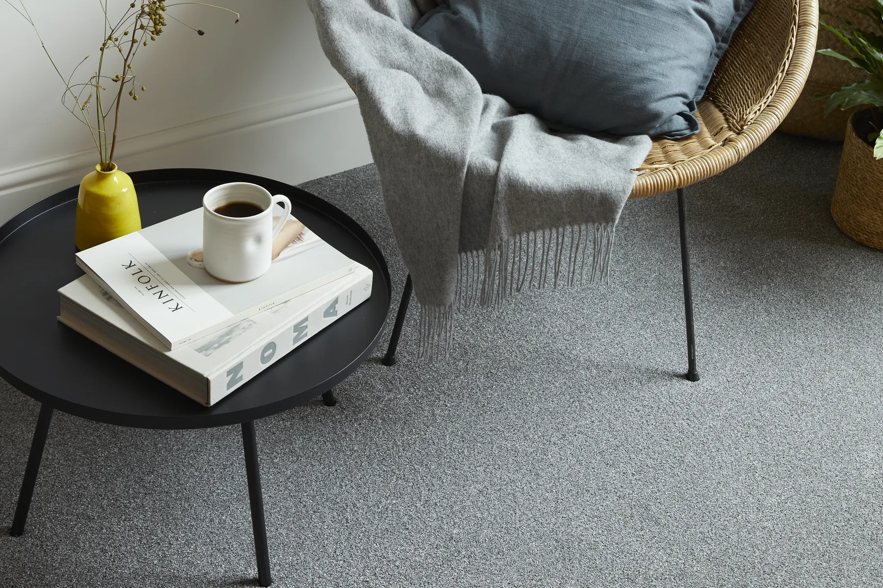 A rattan chair on a grey twist carpet by a window